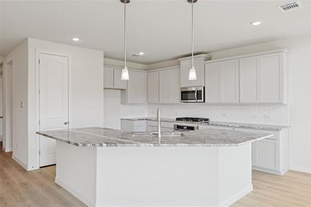 Kitchen with dishwasher, light stone countertops, light hardwood / wood-style floors, and tasteful backsplash