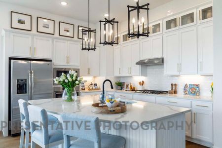 Kitchen with under cabinet range hood, white cabinetry, stainless steel appliances, and backsplash