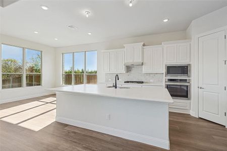 Kitchen with white cabinetry, a kitchen island with sink, wood-type flooring, and appliances with stainless steel finishes