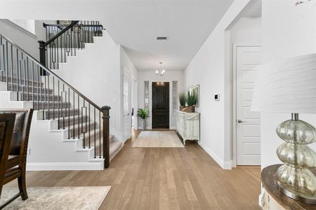 Entryway with light hardwood / wood-style floors and a notable chandelier