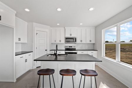 Kitchen featuring sink, a kitchen island with sink, stainless steel appliances, and white cabinetry