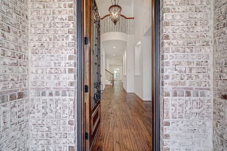 Hallway featuring a chandelier, dark hardwood / wood-style floors, and brick wall