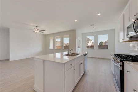 Kitchen featuring appliances with stainless steel finishes, white cabinetry, a kitchen island with sink, and sink