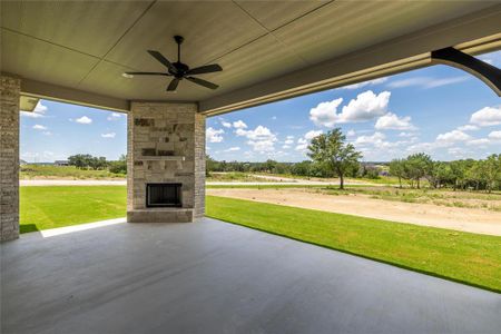 View of patio with ceiling fan, a rural view, and an outdoor stone fireplace