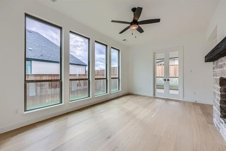 Unfurnished living room with light hardwood / wood-style flooring, a stone fireplace, and plenty of natural light