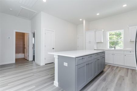 Kitchen with light hardwood / wood-style floors, white cabinetry, sink, a kitchen island, and gray cabinetry