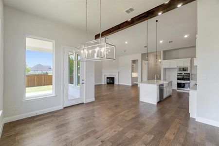 Kitchen featuring white cabinets, hanging light fixtures, a kitchen island with sink, dark hardwood / wood-style floors, and double oven