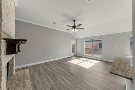 Unfurnished living room featuring lofted ceiling, a stone fireplace, crown molding, light hardwood / wood-style flooring, and ceiling fan