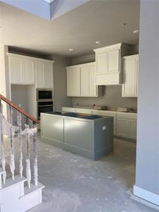 Kitchen with white cabinets, concrete floors, and appliances with stainless steel finishes