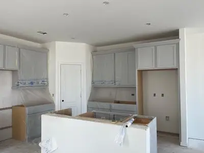 Kitchen featuring a textured ceiling, unfinished concrete flooring, a kitchen island, and gray cabinetry