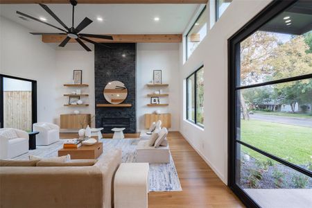 Living room featuring a high ceiling, light wood-type flooring, a wealth of natural light, and a large fireplace