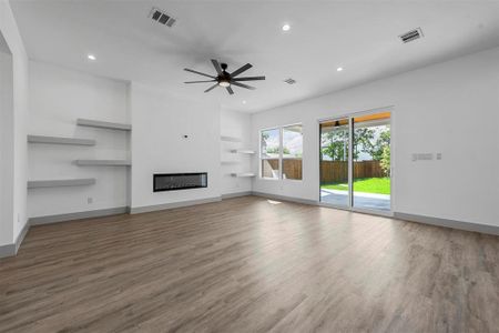 Unfurnished living room featuring built in shelves, ceiling fan, and hardwood / wood-style floors