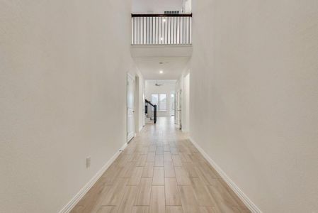 Hall featuring light hardwood / wood-style flooring and a towering ceiling