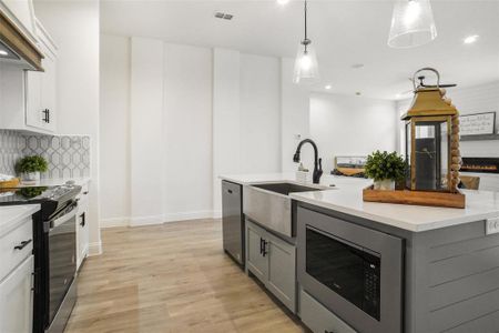 Kitchen featuring decorative light fixtures, built in microwave, black range with electric cooktop, gray cabinetry, and white cabinets