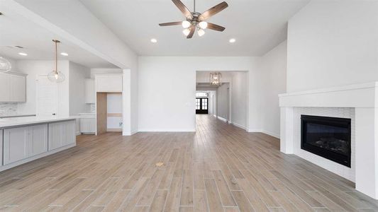 Unfurnished living room with a tile fireplace and ceiling fan