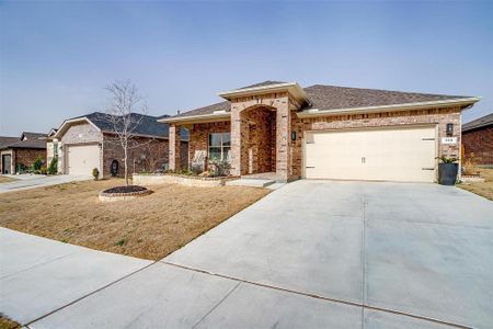 View of front of house with a shingled roof, brick siding, driveway, and an attached garage