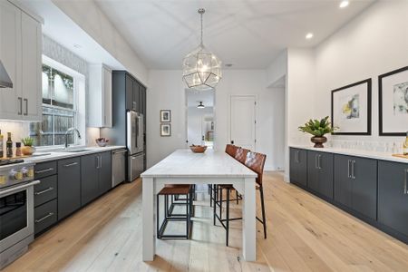 Kitchen with premium appliances, white cabinetry, sink, pendant lighting, and a breakfast bar area