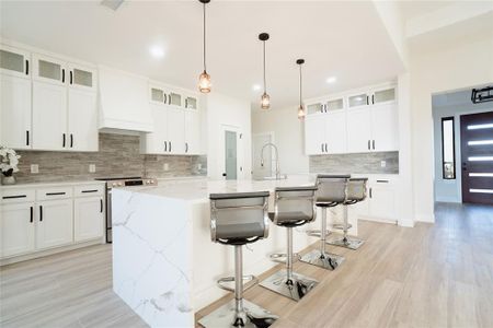 Kitchen with a kitchen island with sink, a breakfast bar, a sink, electric stove, and custom range hood