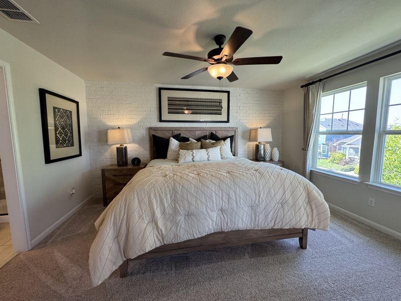 A cozy bedroom with a textured brick accent wall, elegant bedding, and large windows offering natural light. A cozy bedroom with a textured brick accent wall, elegant bedding, and large windows offering natural light.