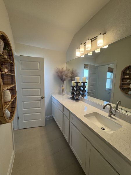 A bright bathroom featuring a long countertop, elegant wall lighting, and stylish decor elements.