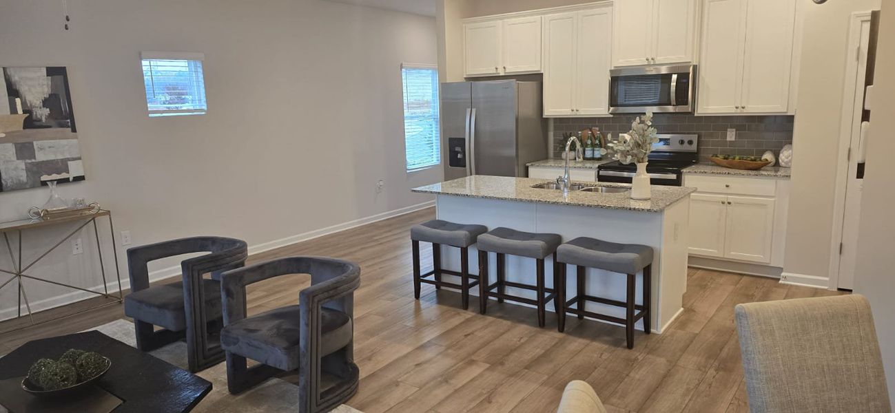 A modern kitchen with granite counter, stainless steel appliances, and cozy seating.