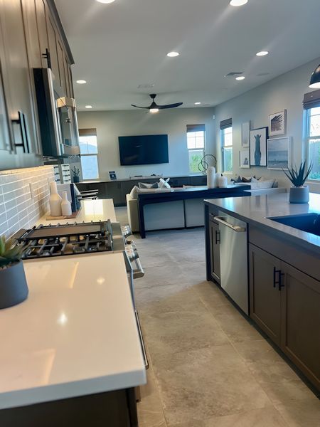 A modern kitchen and living area with sleek cabinets, island seating, and stylish decor. A modern kitchen and living area with sleek cabinets, island seating, and stylish decor.
