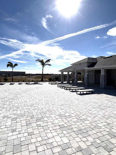 A spacious paved patio area with lounge seating and palm trees in St. Johns Preserve by Landsea Homes (Palm Bay, FL).
