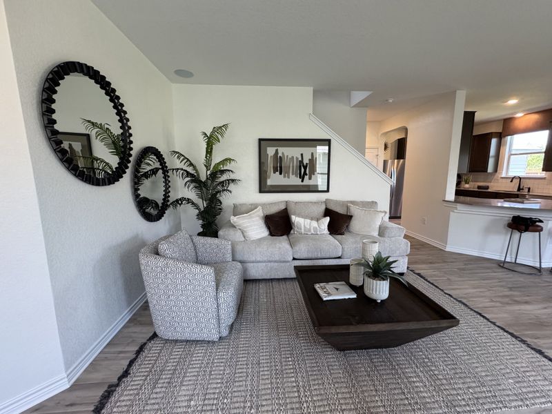 A cozy living area with a plush sofa, patterned chair, and chic decor, leading to a modern kitchen. A cozy living area with a plush sofa, patterned chair, and chic decor, leading to a modern kitchen.