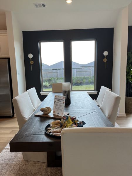 A chic dining area with a dark wood table, white upholstered chairs, and large windows providing natural light. A chic dining area with a dark wood table, white upholstered chairs, and large windows providing natural light.