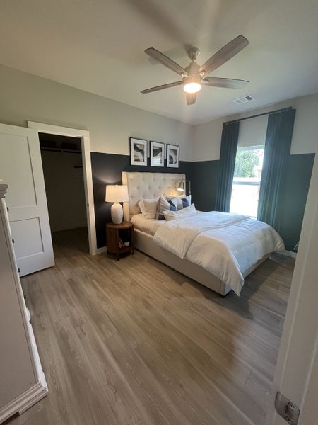 A cozy bedroom with wood flooring, a modern fan, and elegant decor, featuring a plush bed and soft lighting. A cozy bedroom with wood flooring, a modern fan, and elegant decor, featuring a plush bed and soft lighting.