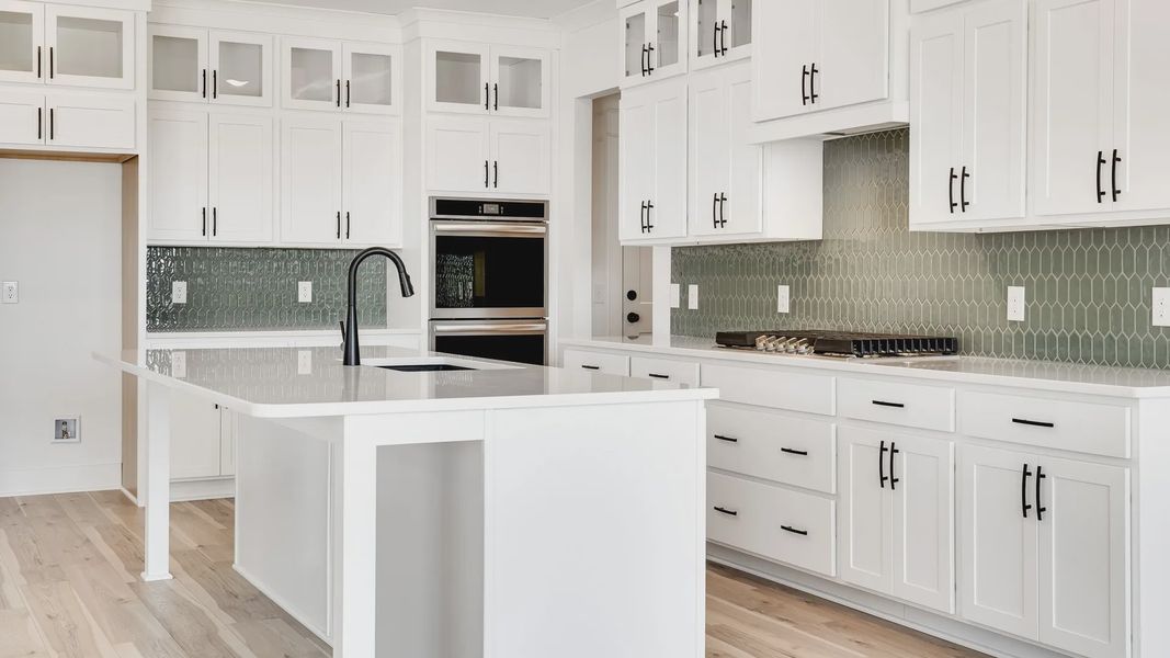 Exquisite white cabinetry and chic green backsplash define this Northridge Park kitchen's elegance and sophistication.