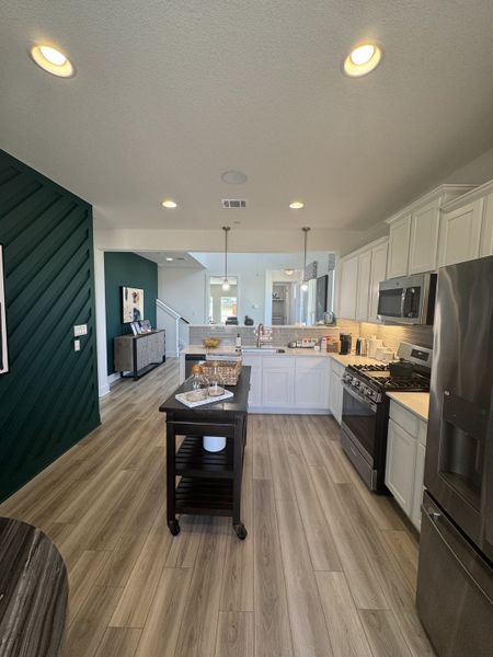 A modern kitchen with sleek white cabinets, stainless steel appliances, and stylish wooden floors.