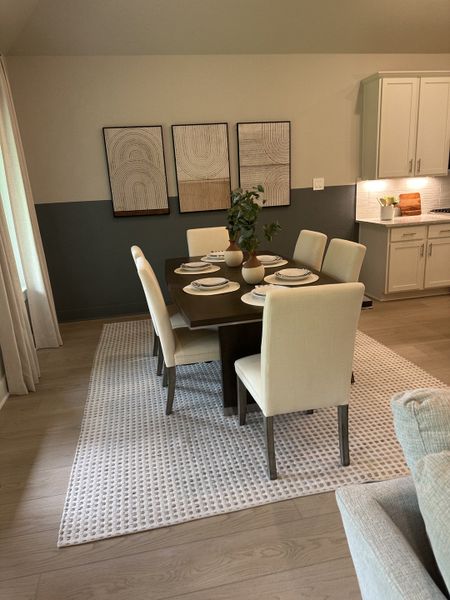 A chic dining area with a dark wood table, cream chairs, and modern art accents on the wall.