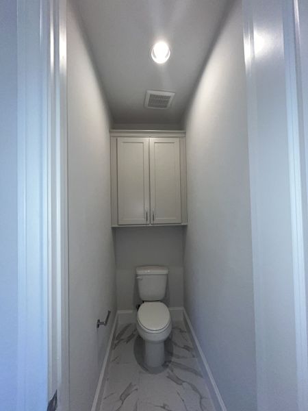 A compact bathroom space with a sleek white toilet, built-in cabinets, and elegant marble tile flooring. A compact bathroom space with a sleek white toilet, built-in cabinets, and elegant marble tile flooring.