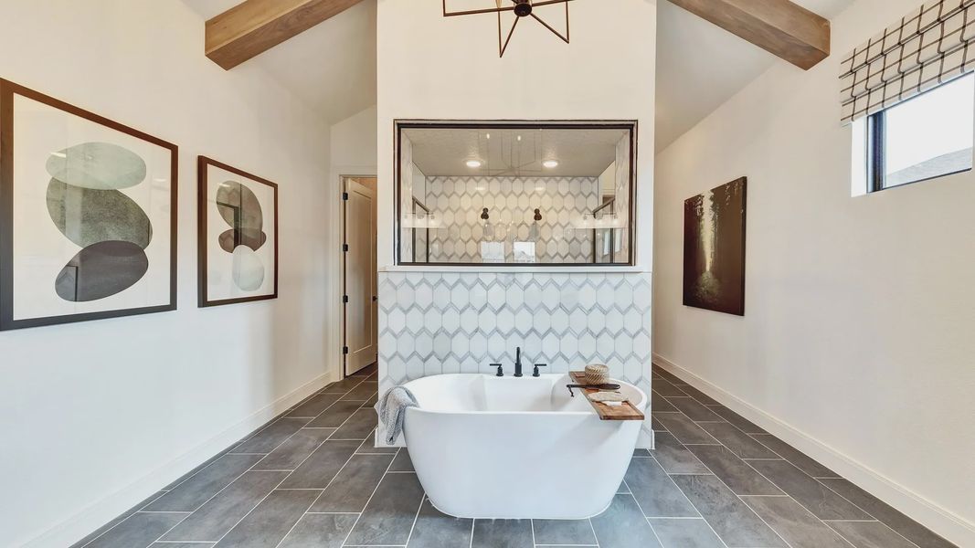 Indulge in Hawkes Landing's elegant bath with freestanding tub, geometric tile, and a chic exposed beam ceiling.
