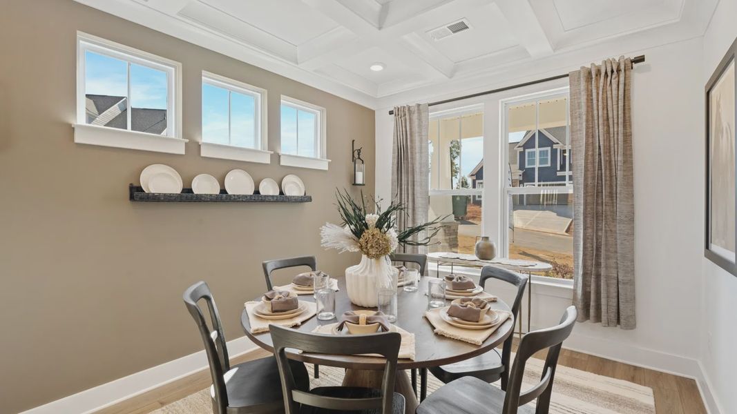 Dining room with multiple windows, elegant, coffered ceiling, and gorgeous hardwood floors at Pleasant Falls by DRB Homes