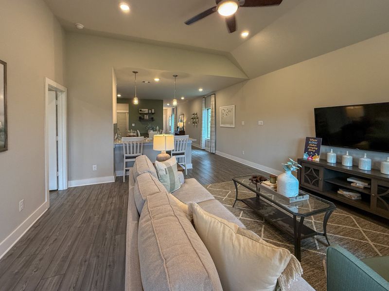 A cozy living area with wood floors, plush seating, and an open-concept design leading to a stylish kitchen.