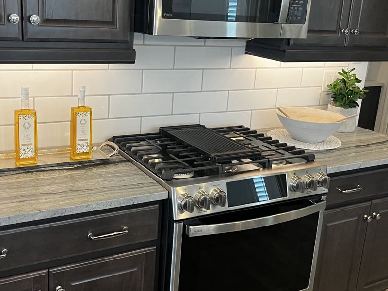 A modern kitchen with dark cabinetry, pendant lighting, and a central island with seating.