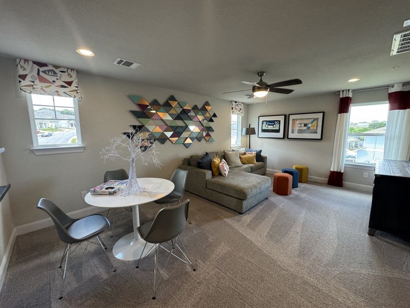 A modern living area with chic wall art, a cozy sectional sofa, and a sleek round dining table set by the window.