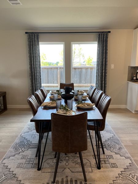 A modern dining room with a wooden table, leather chairs, and large windows, creating a cozy and inviting atmosphere.
