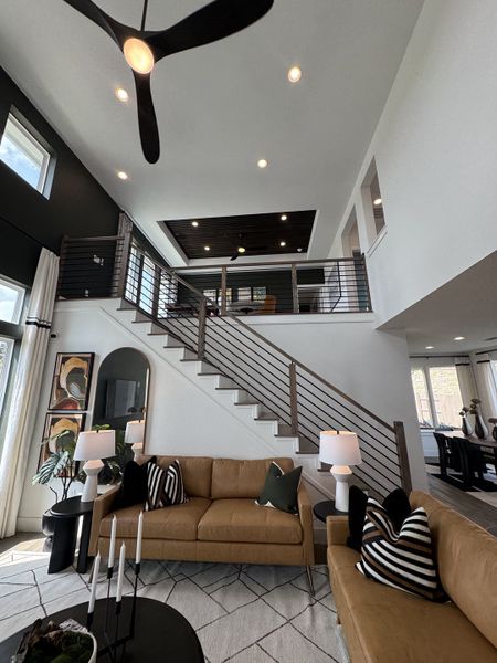 A modern living room with a high ceiling, sleek staircase, and cozy seating, accented by contemporary art and lighting. A modern living room with a high ceiling, sleek staircase, and cozy seating, accented by contemporary art and lighting.