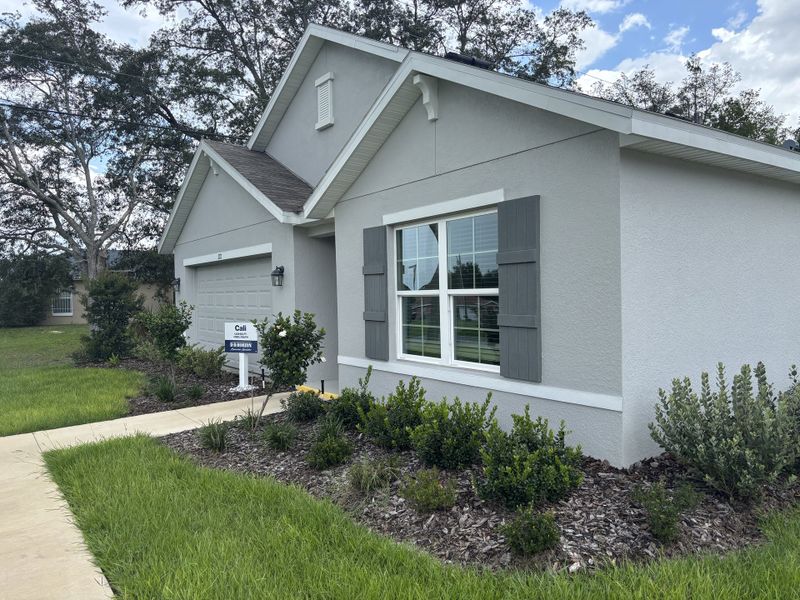 A charming gray home with white accents and lush landscaping in Marion County Spot Lots by D.R. Horton (Ocala, FL).