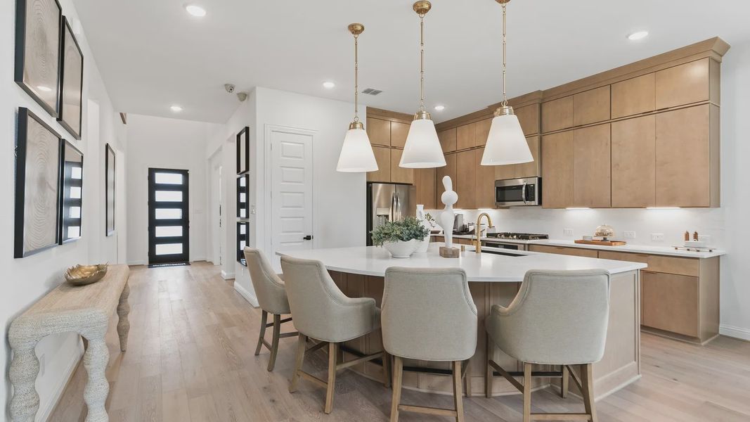 Exquisite quartz island, sleek light wood cabinetry, and elegant lighting in Katy Lakes. Exquisite quartz island, sleek light wood cabinetry, and elegant lighting in Katy Lakes.