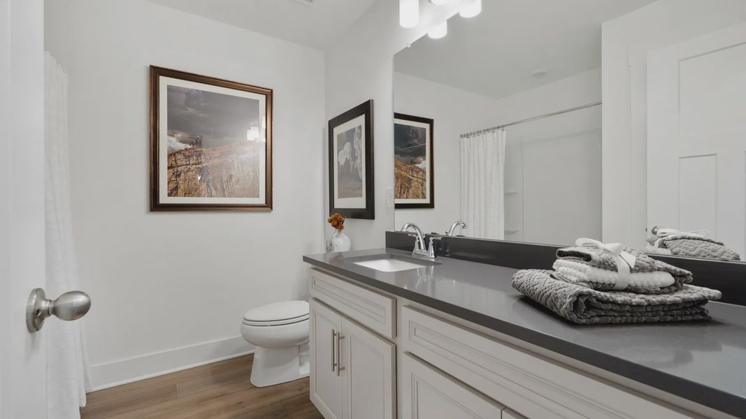 Black granite countertopped large vanity with white cabinetry at Barton Hollow by DRB Homes in Fountain Inn, SC