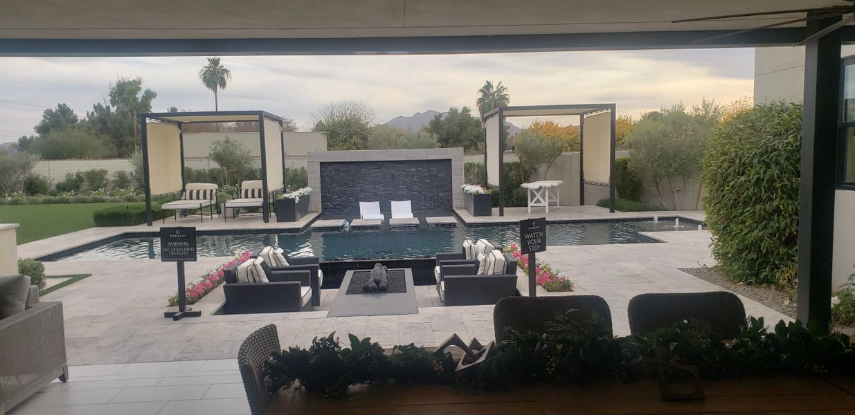 A luxurious patio with a sleek pool, modern seating, and lush landscaping in an elegant setting.