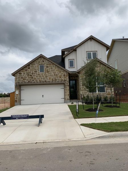 Charming stone exterior home with a spacious driveway in Cedar Brook by M/I Homes (Leander, TX).