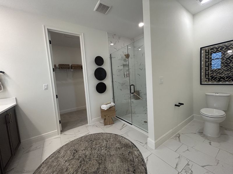 A modern bathroom featuring a glass-enclosed shower, chic tile flooring, and elegant wall decor.