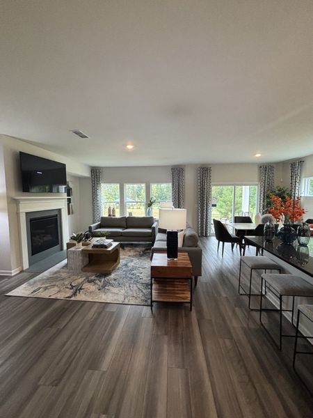 A spacious living area with sleek flooring, fireplace, and ample natural light through large windows.