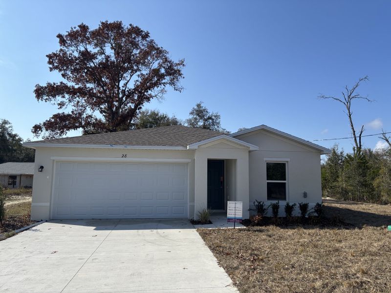 A newly built single-story home with a two-car garage, light exterior, and a simple front yard, set in a suburban setting.