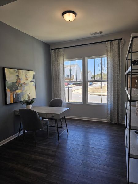 A cozy office nook with a chic desk, modern art, and large windows enhancing natural light.
